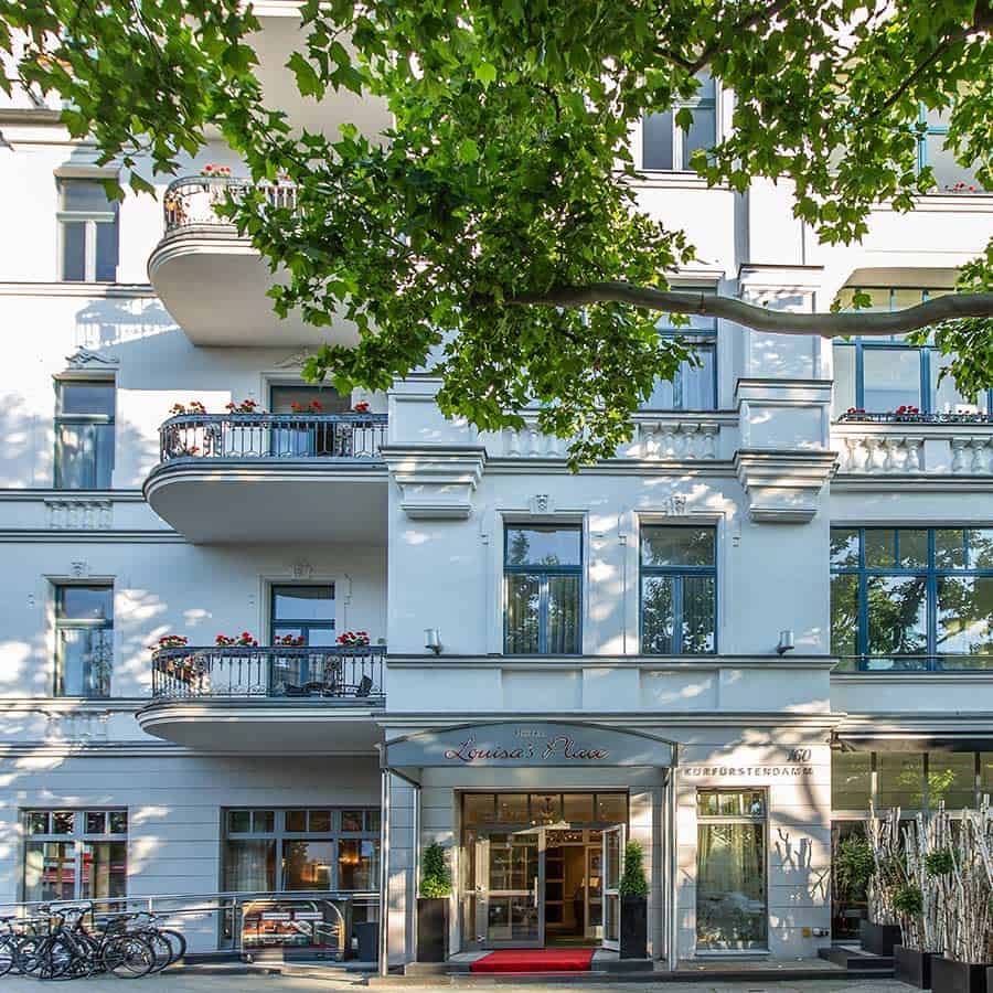 Eingang zum Louisa's Place Hotel, auf dem Kurfürstendamm 160 in Berlin mit rotem Teppich im Eingang und Ahornbaum