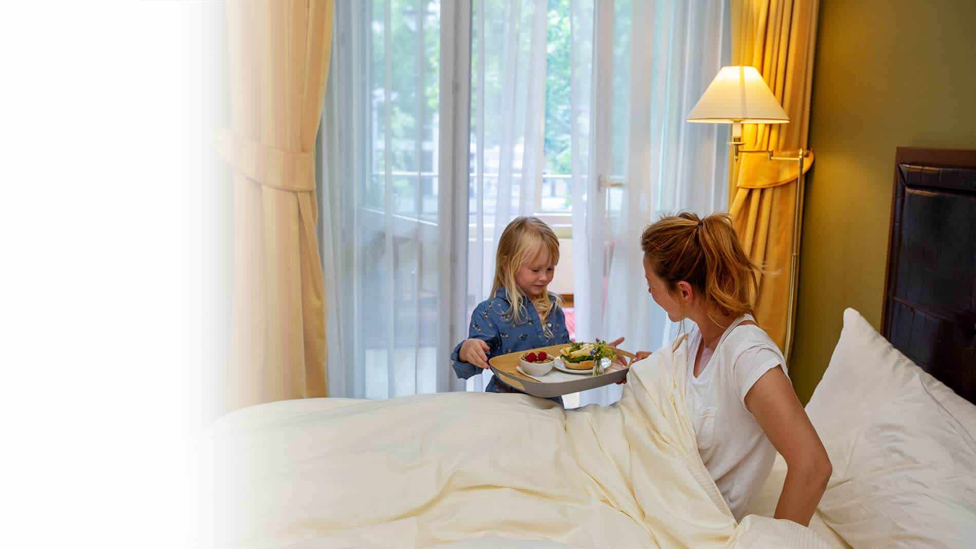 Mädchen bringt Mutter ein Früchstück ans Bett.