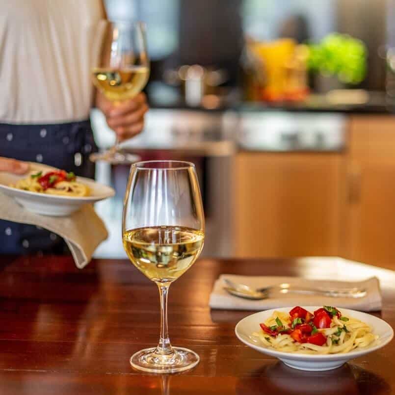 Weißweinglas und ansprechend angerichteter Pastateller in der Küche des Familienzimmers in Louisa's Place Hotel